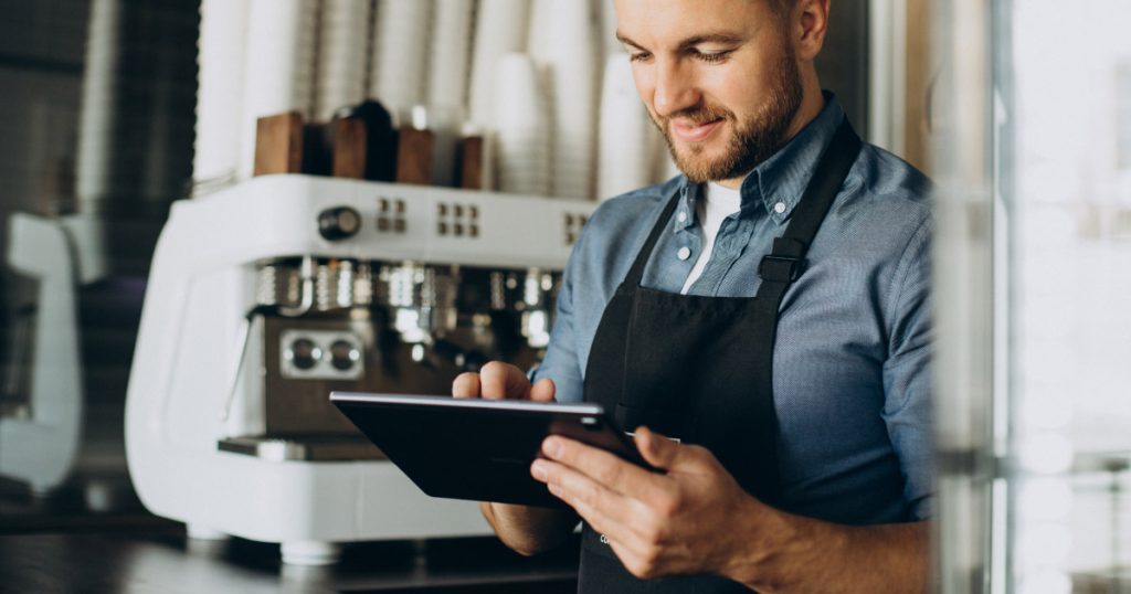 a man uses business tech to take contactless payments at a cafe