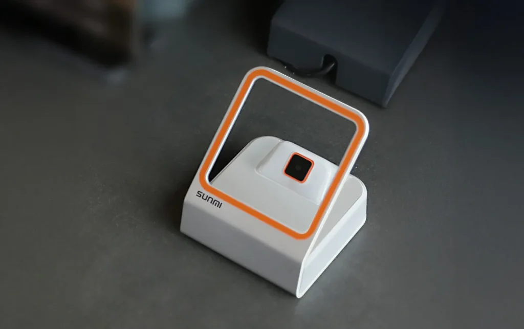 SUNMI BLINK Scanner wireless barcode scanner positioned on retail counter ready for product scanning and inventory management