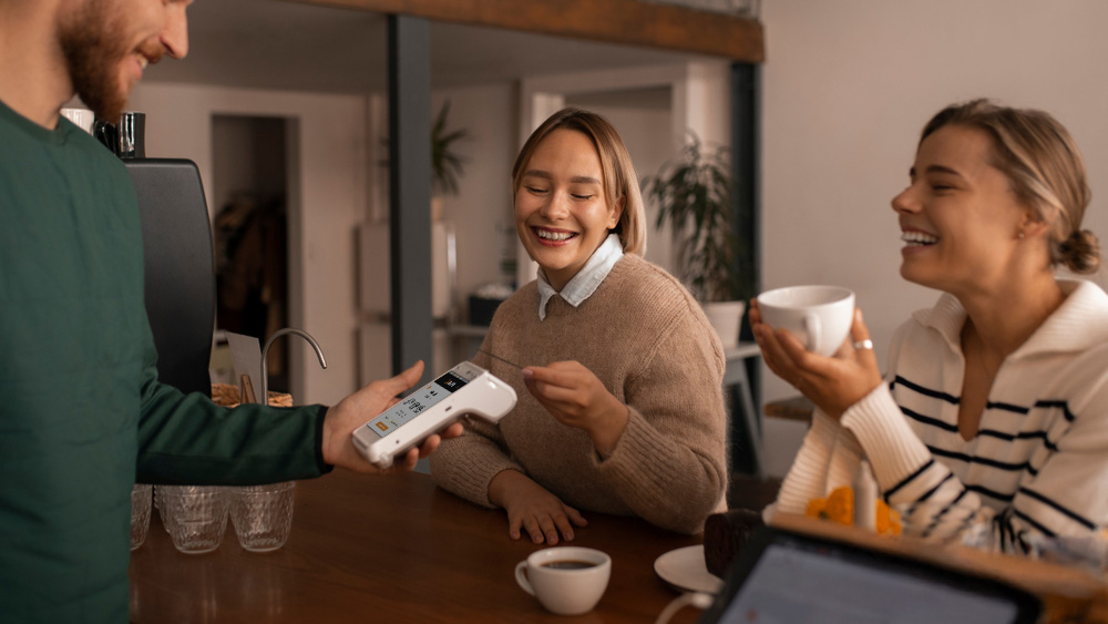 two people making contactless payment at restaurant with waiter holding PAX A920 PRO demonstrating payment security tips and customer trust building