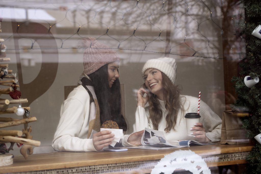 Two friends enjoying coffee in Irish coffee shop during Peak Trading Season Ireland with festive decorations