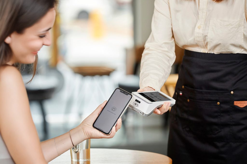 Irish business owner accepting contactless payment with customer reducing transaction fees